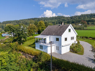 Pen og velholdt enebolig med stor garasje/verksted, uthus og maskinhall/carport. Fantastisk tomt med flott utsikt.