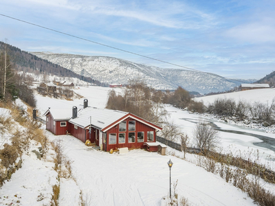 Lom - Bolighus med tilhørende uthus flott beliggende nede ved Bøvra langs Solsidevegen. Stor tomt.