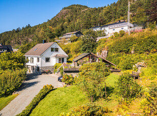 Enebolig med Idyllisk og solrik beliggenhet, stor tomt med flotte hageområder, dobbel car-port, garasje og drivhus.