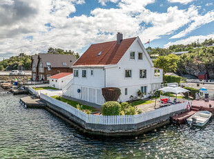 En perle av en eiendom med enebolig med nydelig og solrik hage, strandlinje/stor brygge og garasje.