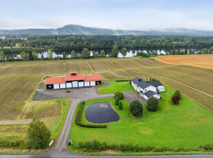 Idyllisk landbrukseiendom langs Glomma. Innholdsrik og flott enebolig. Stort garasje-/verkstedbygg. Ca. 969 mål tomt.